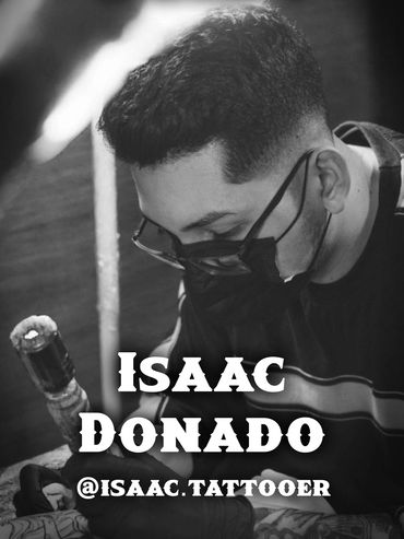 Isaac Donado focused on tattooing while wearing a mask and glasses.