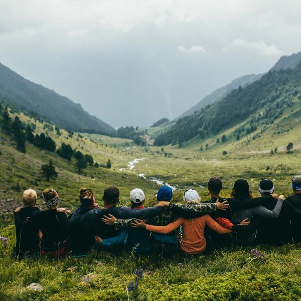 A group of friends sitting and embracing in a scenic mountain valley.