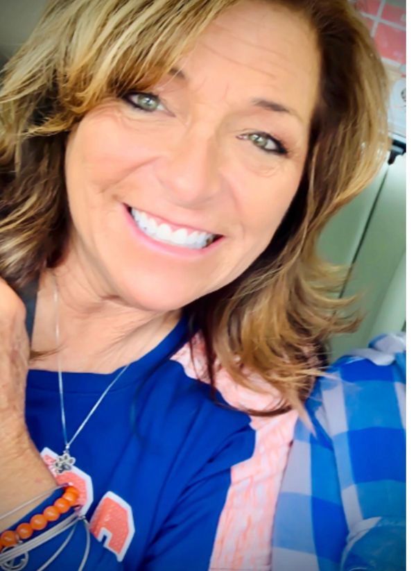 Smiling woman with light brown hair in a blue shirt.