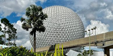 The iconic geodesic sphere of Epcot under a partly cloudy sky.