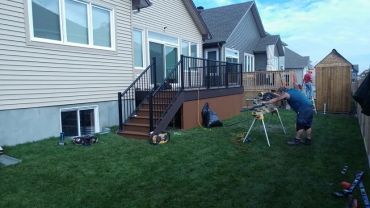 Man working on backyard wood project near house.