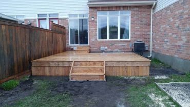 New wooden deck with stairs in a backyard.