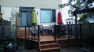 Backyard patio with wooden deck and umbrellas.