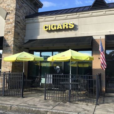 Cigar shop with outdoor seating and yellow umbrellas.