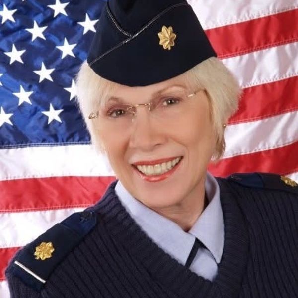Parker in USAF military uniform smiling with American flag background.