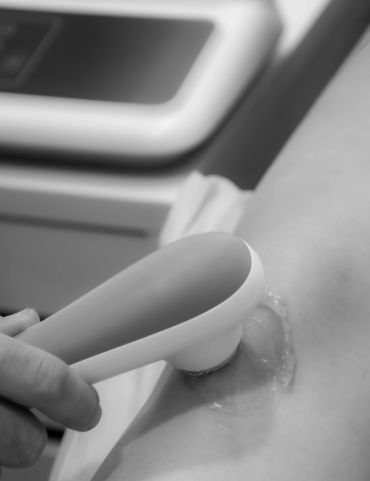 Ultrasound probe scanning a patient's skin with gel applied.