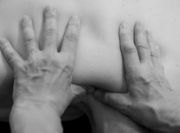 Hands pressing on a person's back in a massage therapy session.