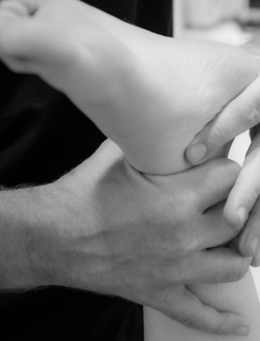 Close-up of hands massaging a foot in black and white.
