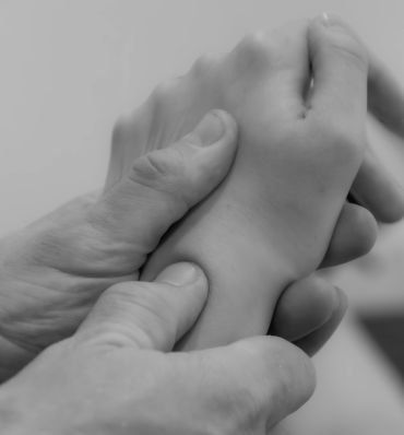 Close-up of a hand gently holding a smaller hand, symbolizing care and support.