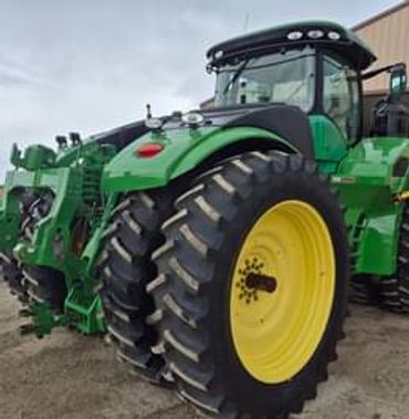 Large green tractor with yellow wheels parked outdoors.