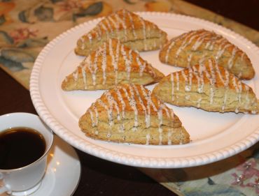 Freshly baked scones with icing drizzle on a plate.