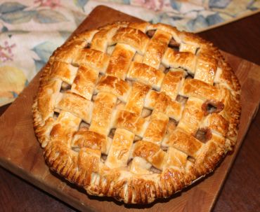 Golden lattice top apple pie on wooden board.