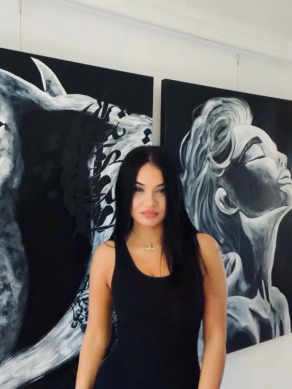 Jeune femme devant des peintures murales en noir et blanc.