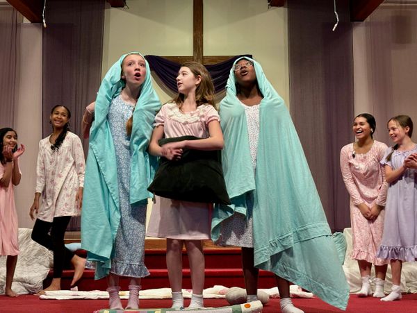 Children performing a joyful play on stage with costumes and props.