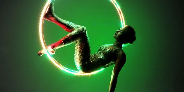 Performer poses inside a glowing ring with green lighting.