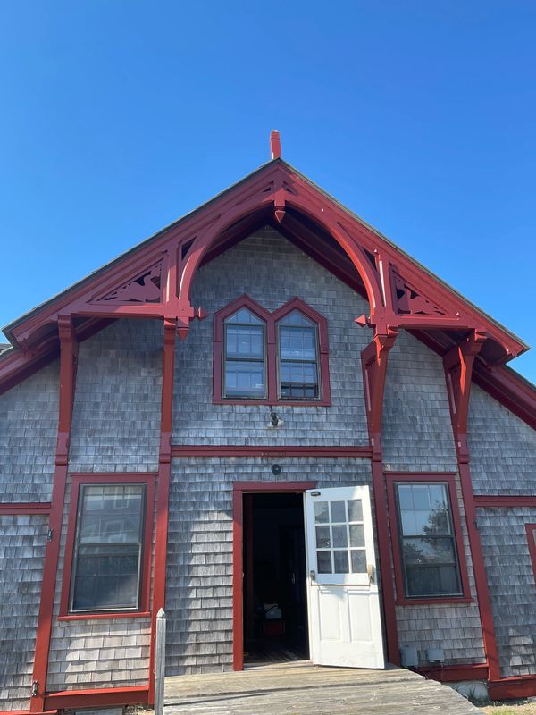 Historic building with red trim and open white door under clear blue sky.