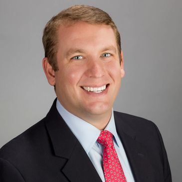 Smiling man in suit and red tie.