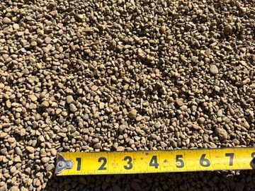 Yellow measuring tape on small brown gravel stones.