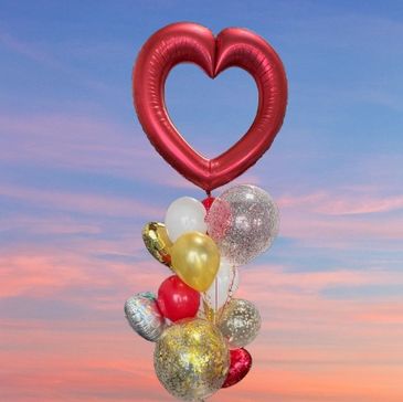 Heart-shaped and colorful balloons against a sunset sky.