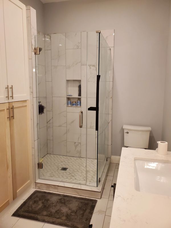 Modern bathroom with a glass shower enclosure and marble tiles.