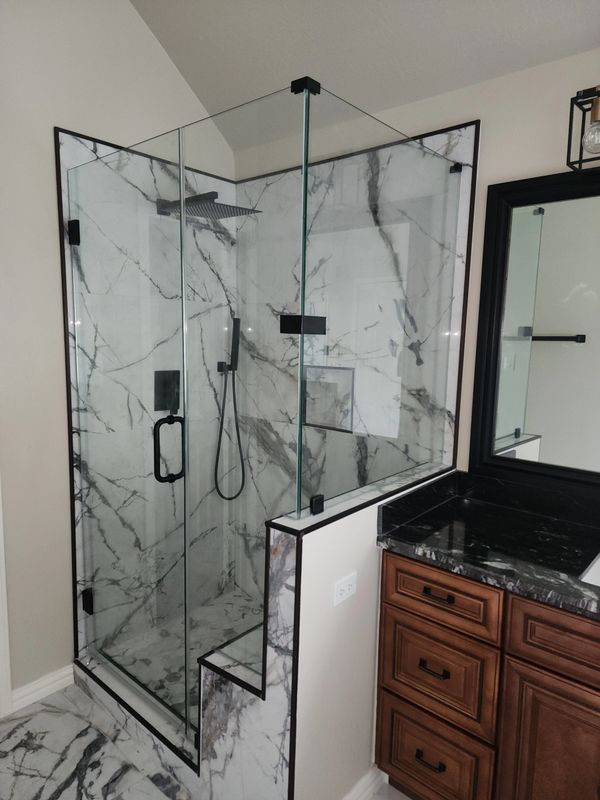 Modern bathroom shower with glass doors and marble walls.