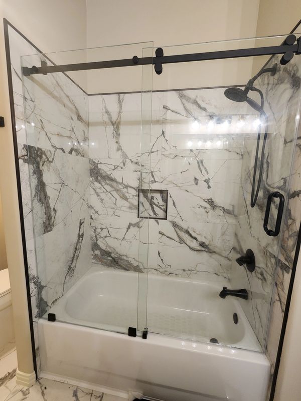 Modern bathroom with marble tiles and glass shower enclosure.