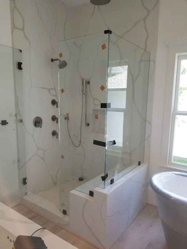 Modern bathroom with glass shower enclosure and marble walls.