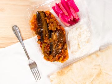 eggplant with tomato garlic and onions and a side of rice, turnip pickles, and pita bread