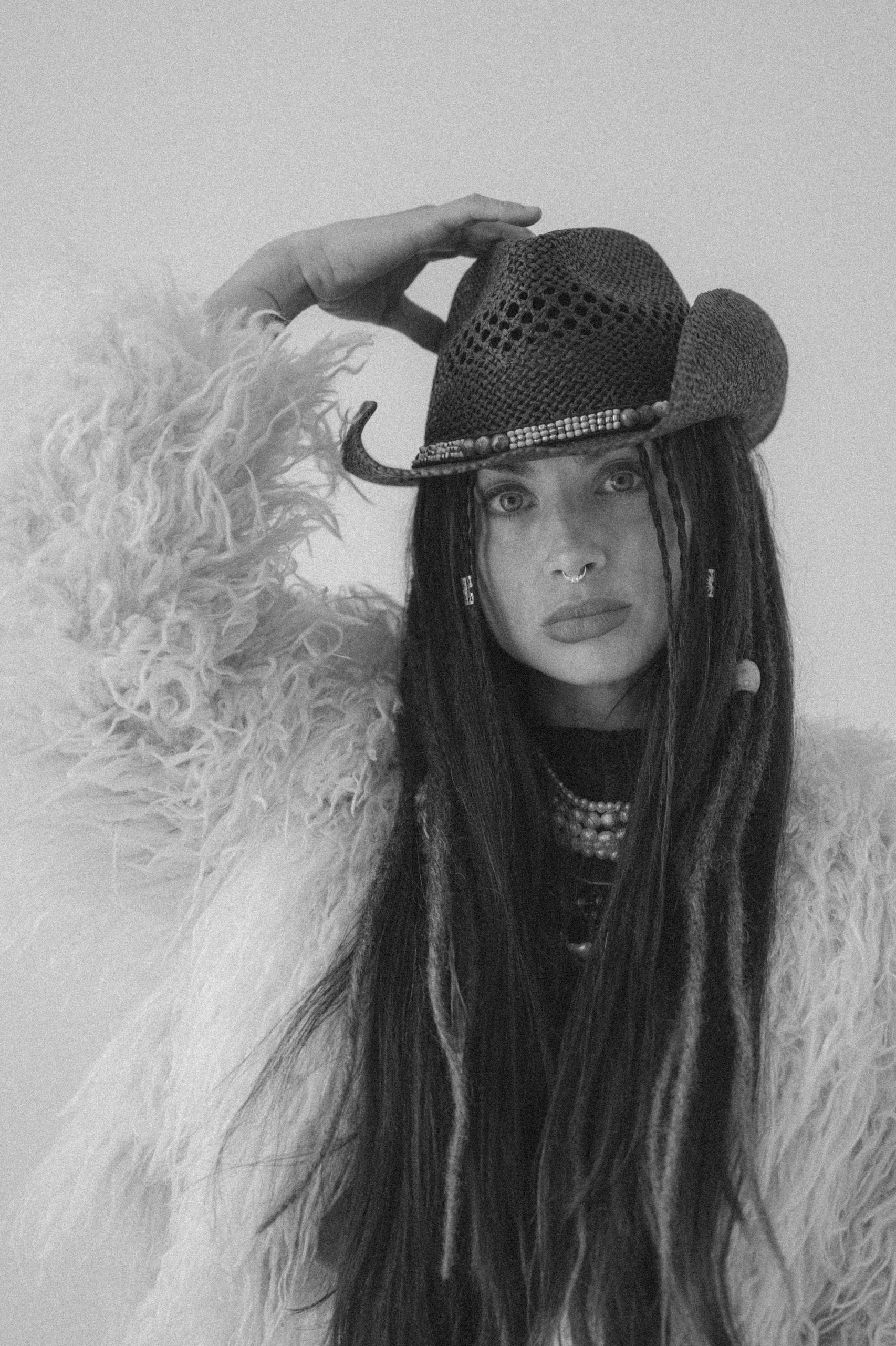 Person in a textured coat and cowboy hat, gazing intensely at the camera.