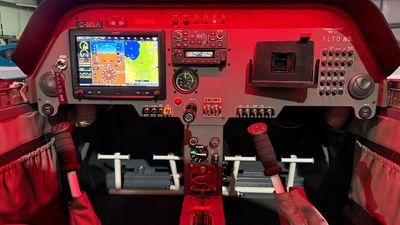 Cockpit of a small aircraft illuminated with red lighting and digital displays.