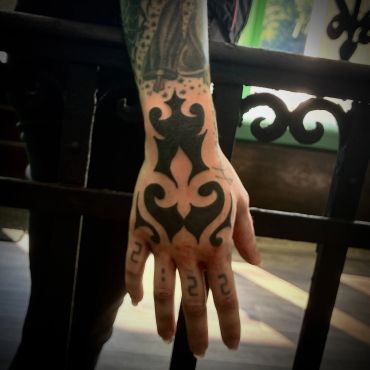 Hand with tribal tattoos and numeric finger tattoos.