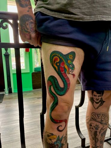 Colorful snake tattoo on thigh.
