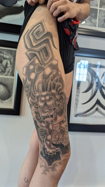 Detailed black and gray tattoo of a fierce mythical lion on a thigh.