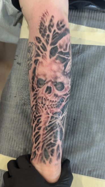 A detailed skull tattoo with intricate shading on a forearm.