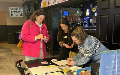 Three women engaged in paperwork at a cafe table.