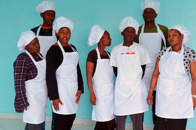 Young men and women wearing chef hats and white aprons