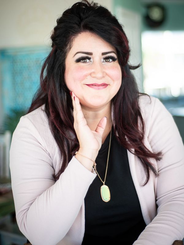 Smiling woman with long dark hair and a pendant necklace.