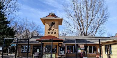 Entrance of Pueblo Zoo with clear blue sky and leafless trees.