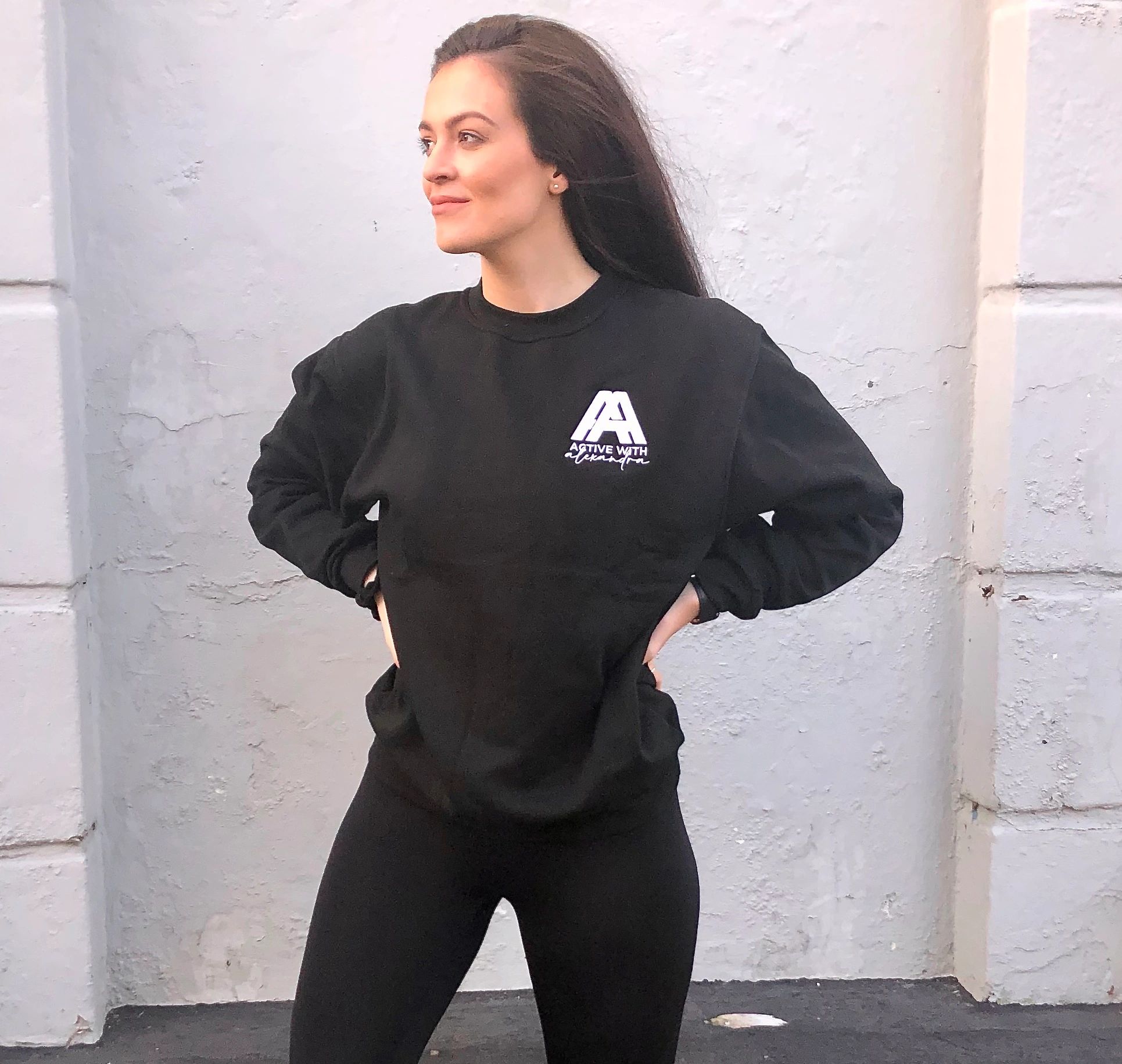 Woman in black athletic wear posing confidently outdoors.