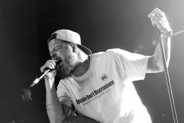 Man singing into microphone on stage.