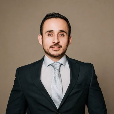 Professional man in a suit and tie against a plain background.