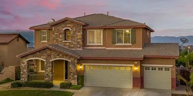 A two-story suburban house with stone accents and a three-car garage at sunset.