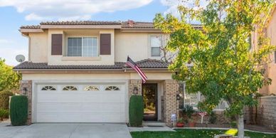 Two-story suburban house with a garage and a front yard tree.