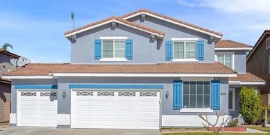Two-story house with blue shutters and a three-car garage.