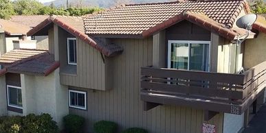 Apartment building with balconies and tiled roof under clear sky.