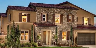 Modern two-story house with stone and stucco facade at dusk.