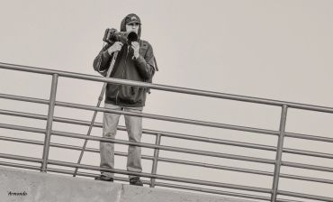 Person wearing a mask and holding a camera on a rooftop.