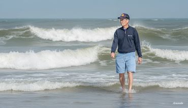 Man walking in shallow ocean water on a sunny day.