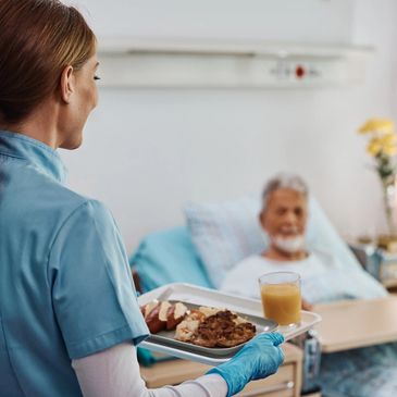 Nurse delivering a meal tray to a patient in a hospital room.