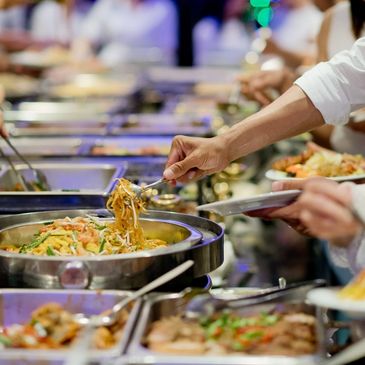 Person serving noodles from a buffet line.